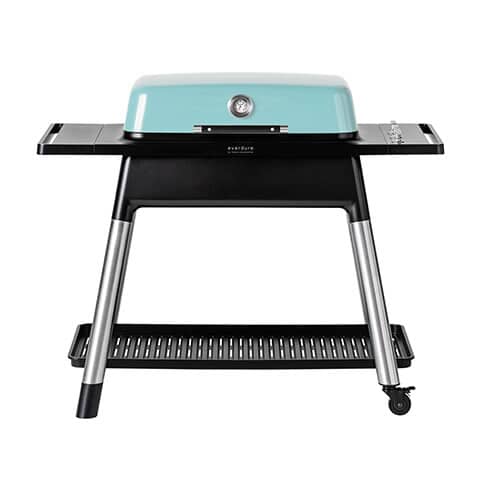 Mint-colored 3-burner gas BBQ with stainless steel accents, a built-in thermometer, and a sturdy black frame on wheels, featuring side shelves for extra workspace.