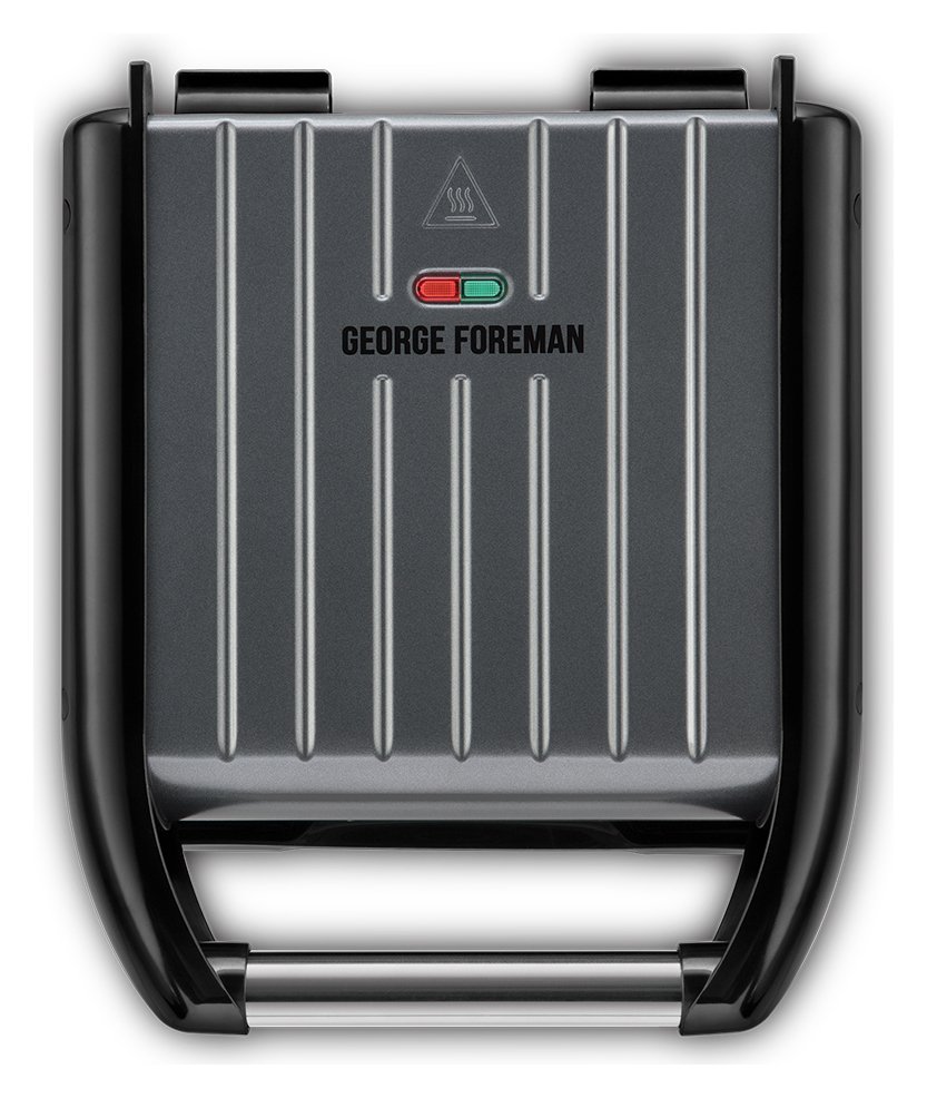 Small grey steel grill with a ribbed cooking surface, featuring a black handle and red/green indicator lights, branded with "GEORGE FOREMAN" on the top.