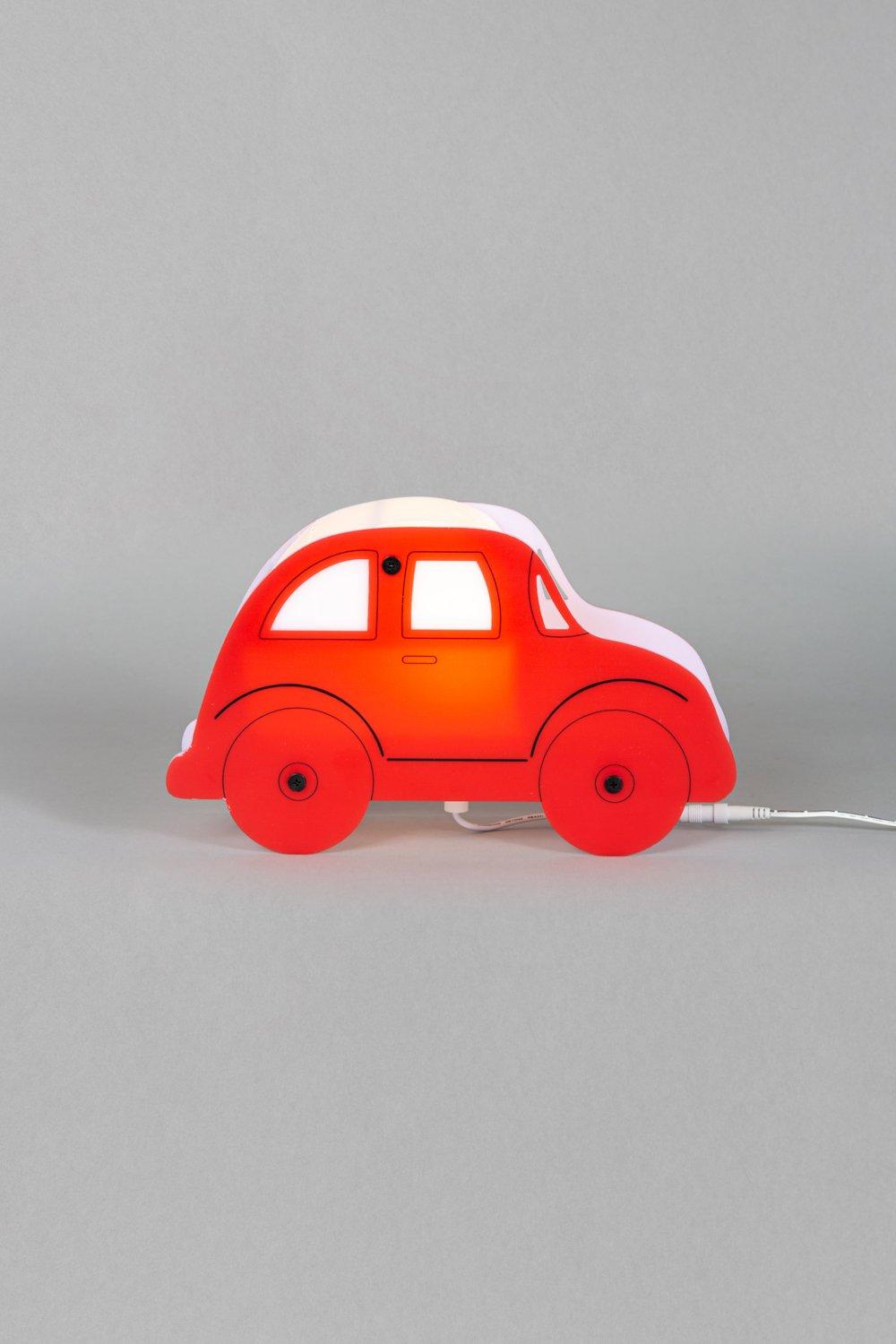Red car-shaped table lamp with a glossy finish, featuring black wheels and a white top, designed to emit a warm glow when plugged in.