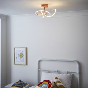 Pink flush ceiling light with a whirly design, featuring curved LED strips, mounted on a round base, illuminating a cozy bedroom with a bed and colorful decor.