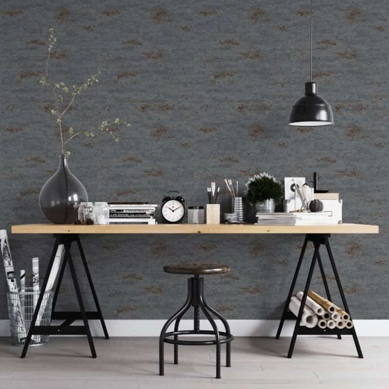 Distressed concrete stone textured wallpaper in charcoal grey with copper accents, featuring a modern workspace with a wooden table, black pendant light, and decorative plants.