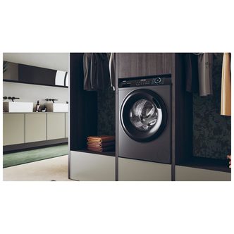 Graphite-colored 10kg Haier washing machine with a 1400 spin speed, featuring a large circular door and a sleek control panel, set in a modern laundry space.