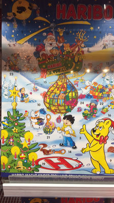Colorful Advent calendar featuring Haribo characters, festive scenes with Santa, a Christmas tree, and numbered doors revealing jelly candies, set against a snowy background.