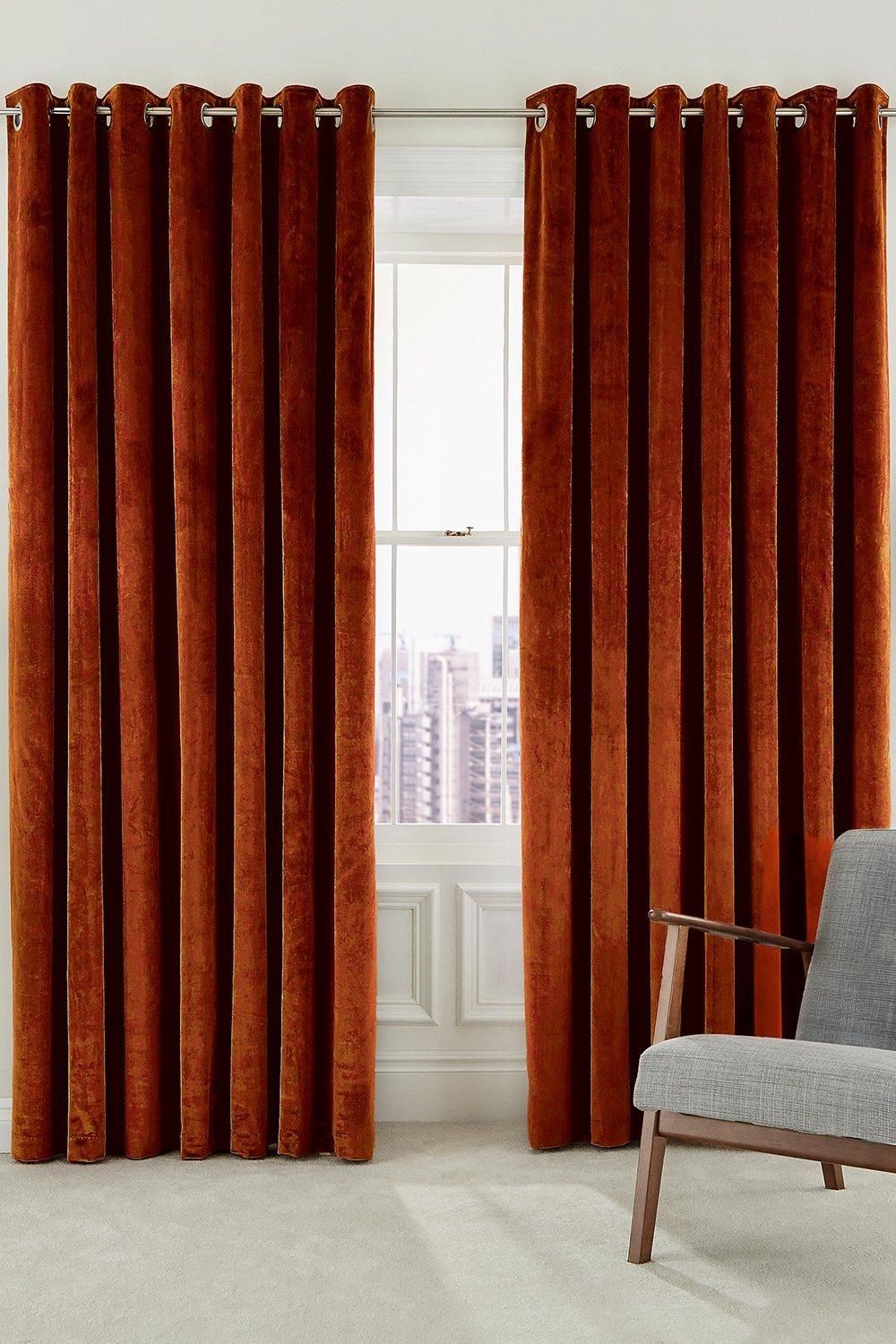 Woven lined curtains in rich copper hue, featuring a luxurious velvet texture, with a size of 228cm width and 228cm drop, elegantly hanging from silver eyelet rings.