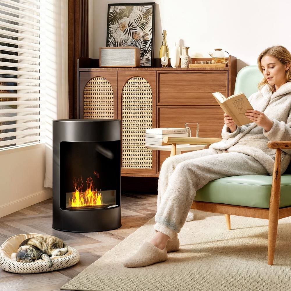 Black HOMCOM 22" bioethanol fireplace stove with a glass front, emitting flames, placed in a cozy room beside a woman reading in a chair, with a cat resting nearby.