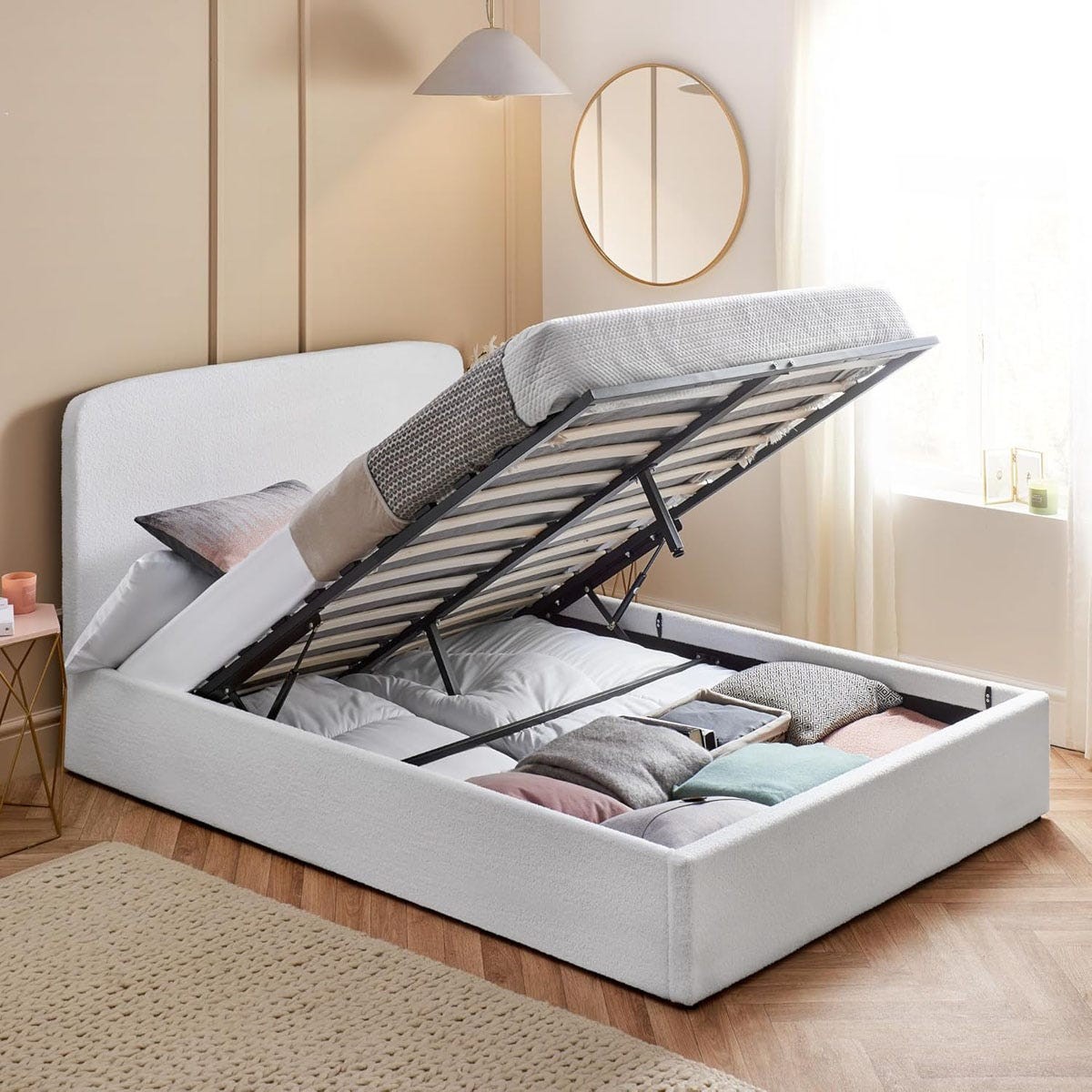 Double white boucle ottoman bed frame with a lift-up storage feature, showcasing a soft fabric finish and a spacious interior for bedding or belongings, set in a bright room.