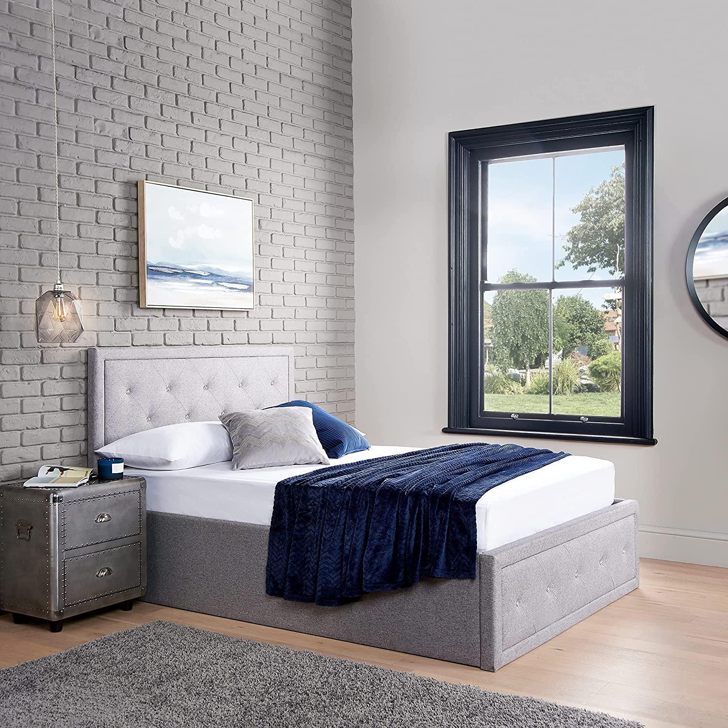 Double ottoman storage bed frame in crystal grey fabric with a tufted headboard, featuring a spacious storage compartment and complemented by a blue throw blanket.