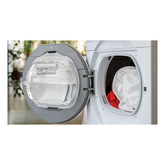Front-loading washing machine with a transparent round door, showcasing white and red laundry inside, set against a bright, indoor background.