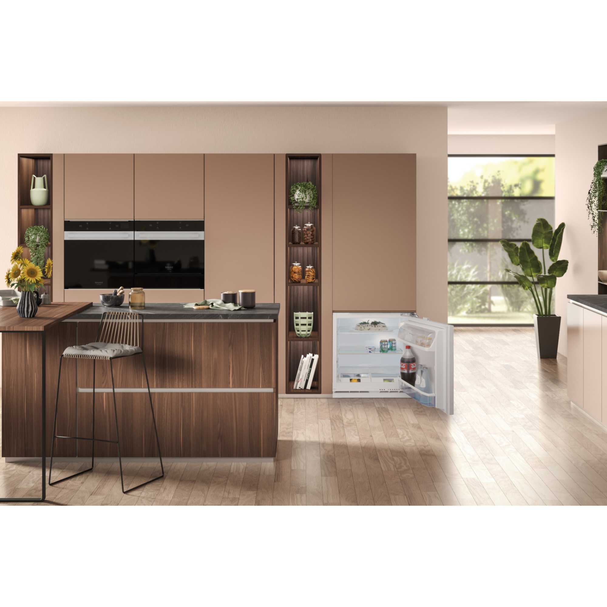 Hotpoint 144 Litre Integrated Under Counter Fridge in white, featuring a clear glass shelf, adjustable door bins, and a sleek design, seamlessly integrated into a modern kitchen setting.