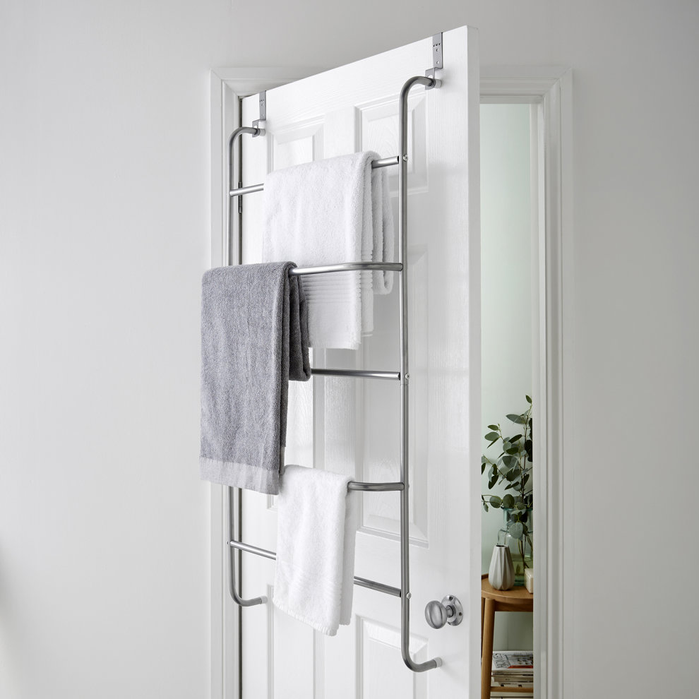 Ricomex 4-tier over-door bar in silver powder-coated metal, featuring four horizontal bars holding gray and white towels, mounted on a white door.