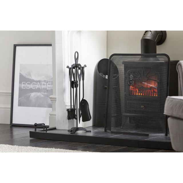 Heavy duty black fireplace tool set by Inglenook Fireside, featuring a stand with a shovel, poker, and tongs, positioned beside a black wood-burning stove and a decorative framed print.