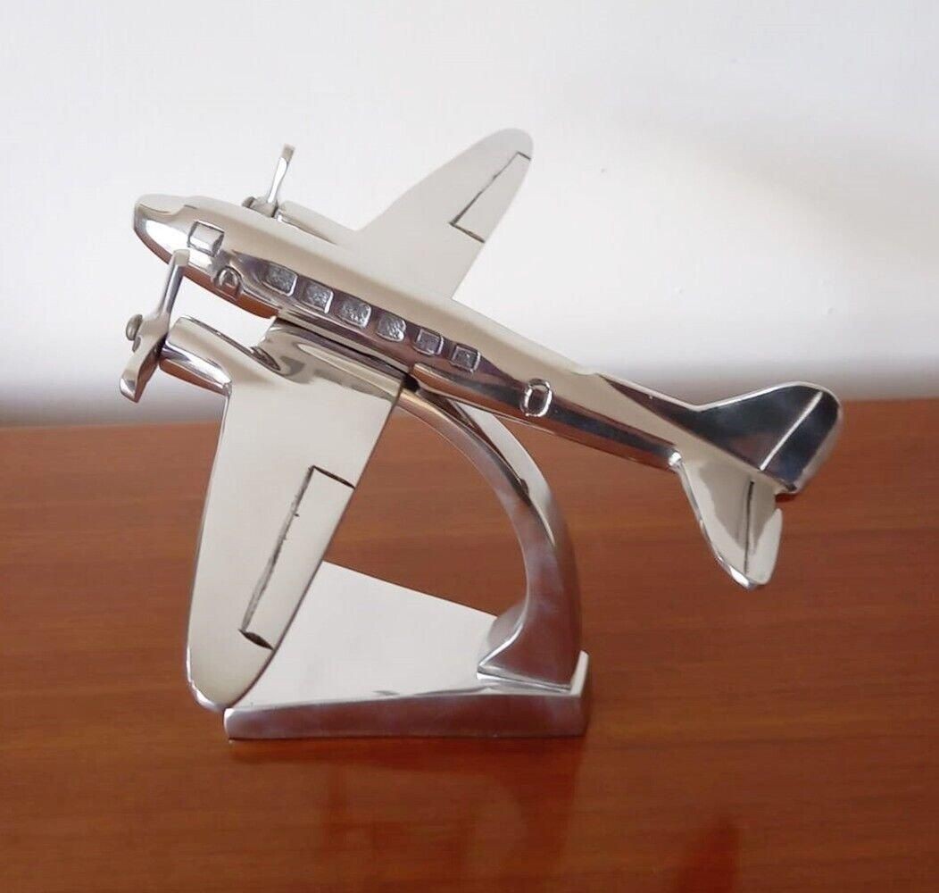 Aluminium Douglas DC3 aeroplane ornament with a polished silver finish, featuring detailed windows and a sleek design, mounted on a sturdy base.