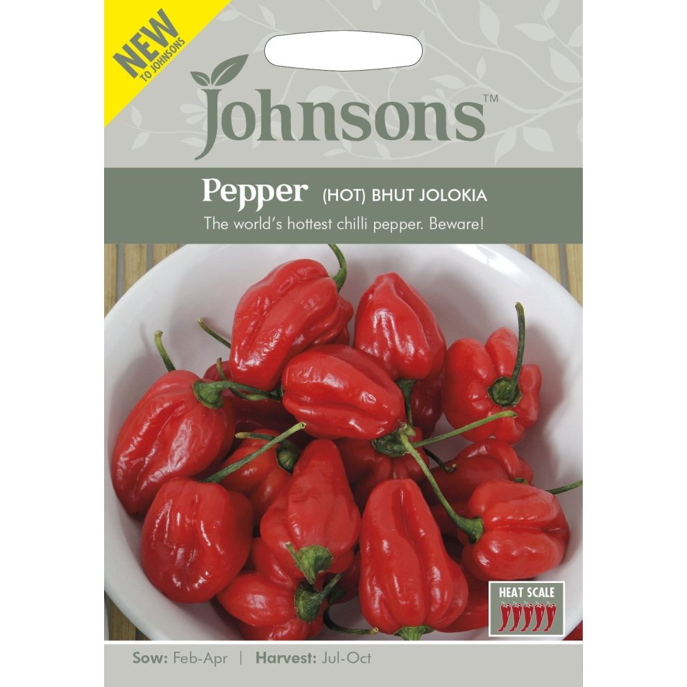 Bright red Bhut Jolokia peppers displayed in a white bowl, with a green and gray seed packet featuring the Johnsons logo and details about sowing and harvesting.