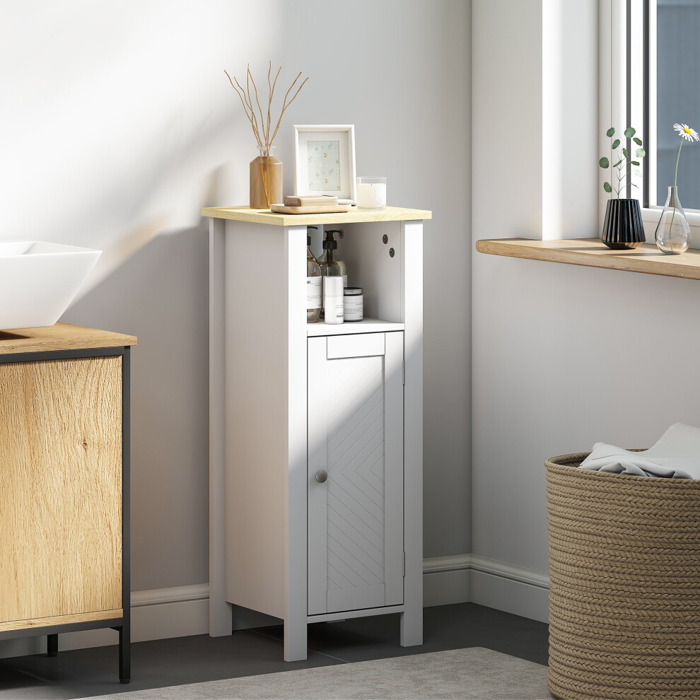 Narrow white bathroom storage cabinet with an open shelf, wooden top, and a door featuring a diagonal pattern, set in a bright, modern bathroom.
