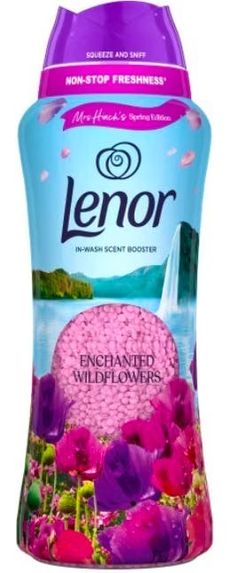 Bright pink bottle of Lenor Beads Enchanted Wildflowers, featuring a scenic backdrop of flowers and a waterfall, with a purple cap and "squeeze and sniff" label.