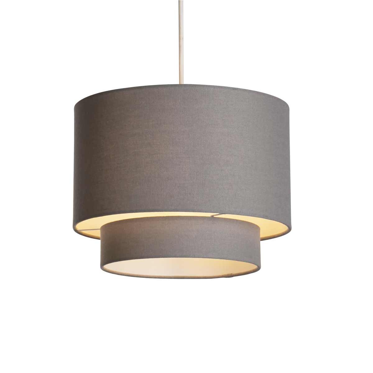 Grey two-tier drum shade lamp featuring a linen texture, with a larger outer shade and a smaller inner shade, providing a soft, warm glow.