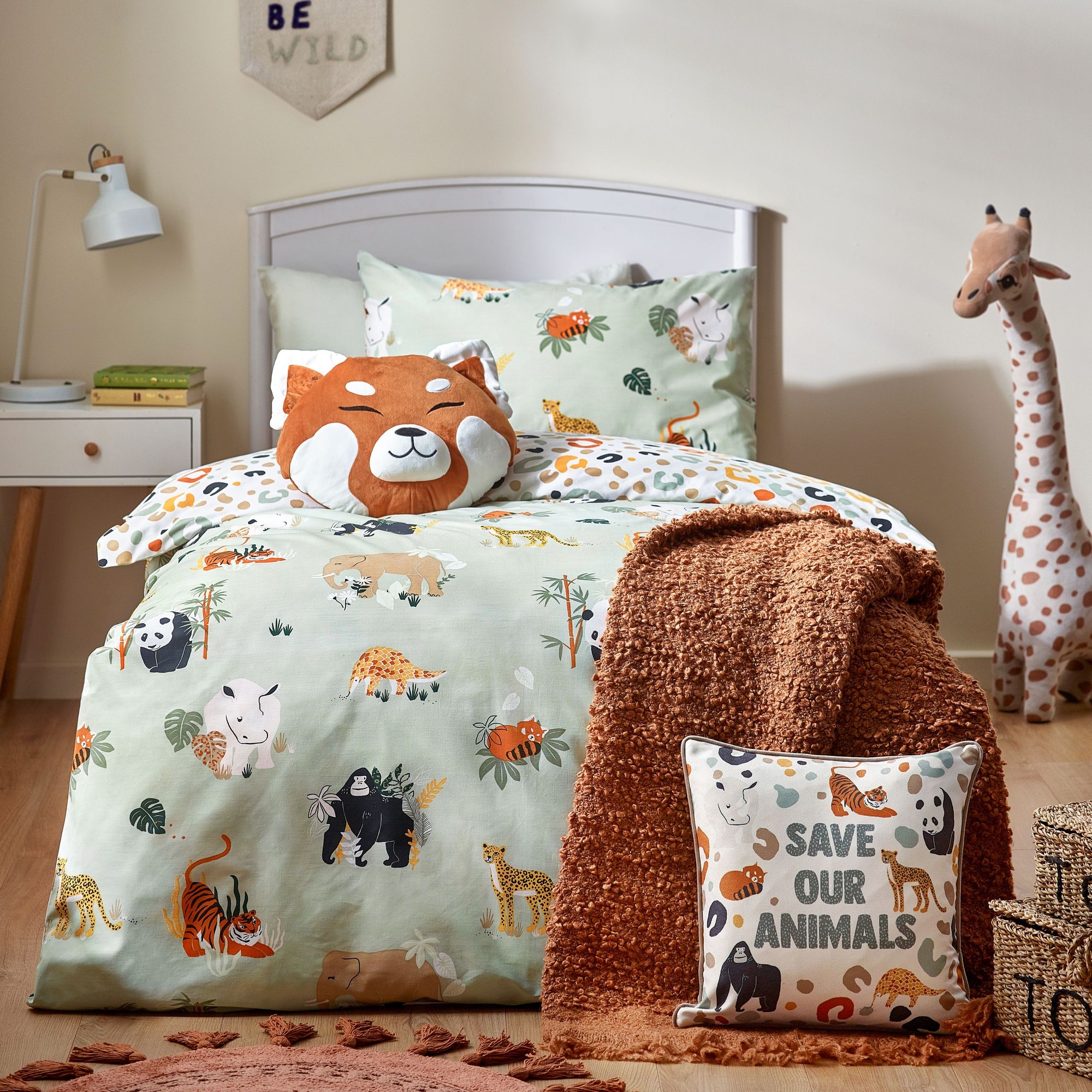 Reversible double duvet cover set featuring colorful wildlife animals on a green background, complemented by a plush orange bear pillow and a "Save Our Animals" cushion.