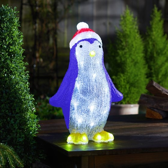 A colorful illuminated penguin decoration with a purple body, white belly, and red-and-white striped hat, featuring built-in lights for a festive glow.
