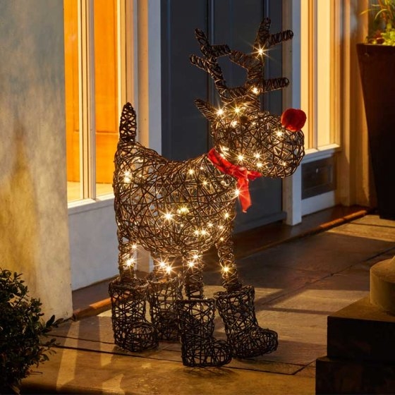 Sparkly Rudolph features a black wireframe design adorned with 80 warm white LEDs, a red nose, a red scarf, and black boots, standing by a doorway.