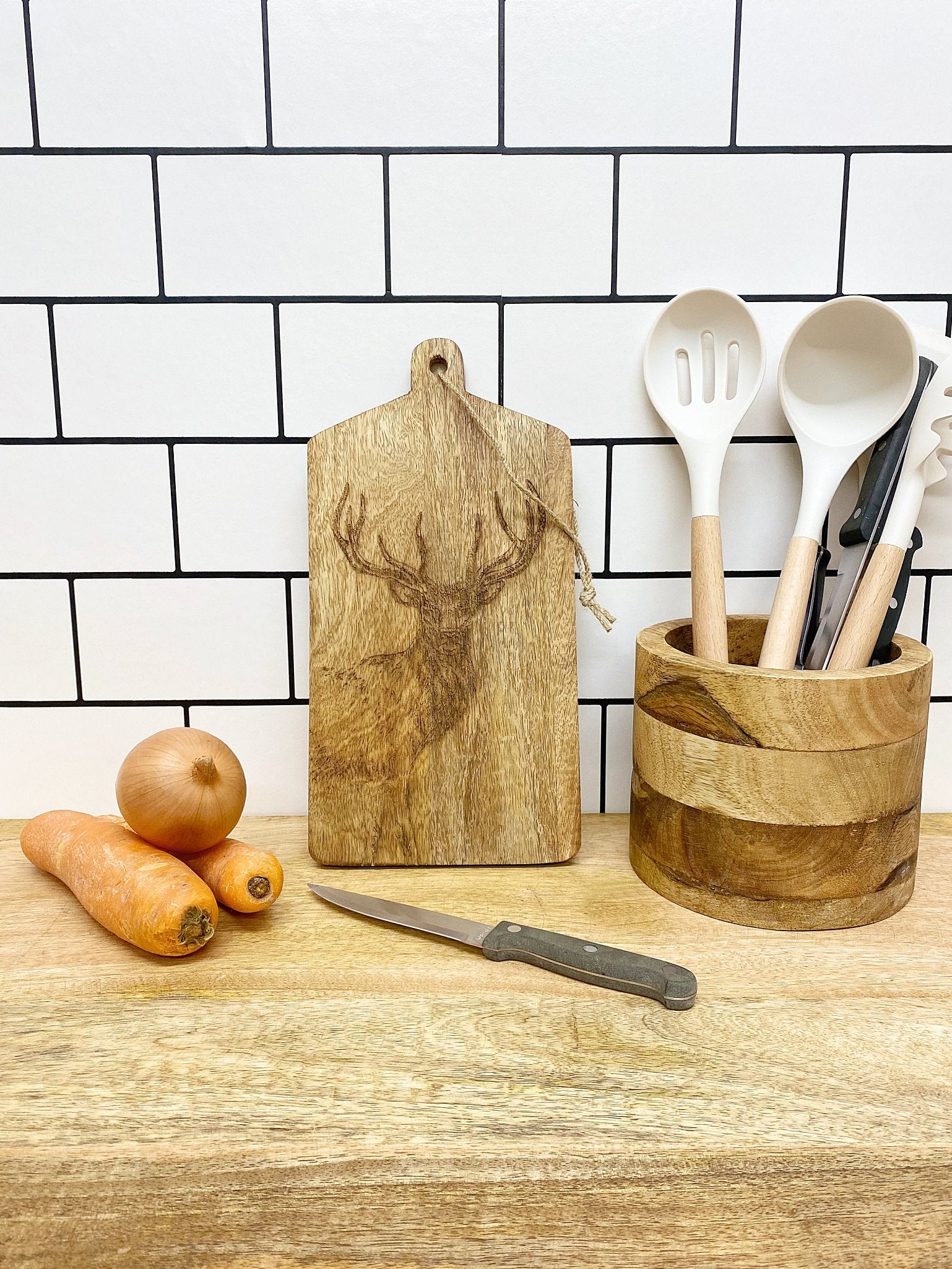 30cm wooden cheese and chopping board featuring a stag design, with a natural wood finish, alongside carrots, onions, a knife, and wooden utensils in a round holder.