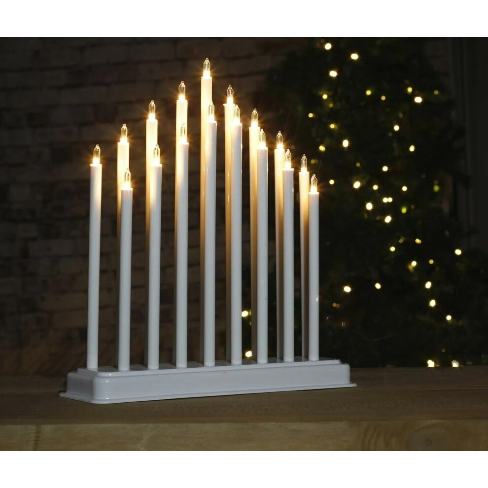 White LED candle bridge arch tower with 17 glowing candle-like lights, battery-operated, set against a blurred backdrop of twinkling lights.