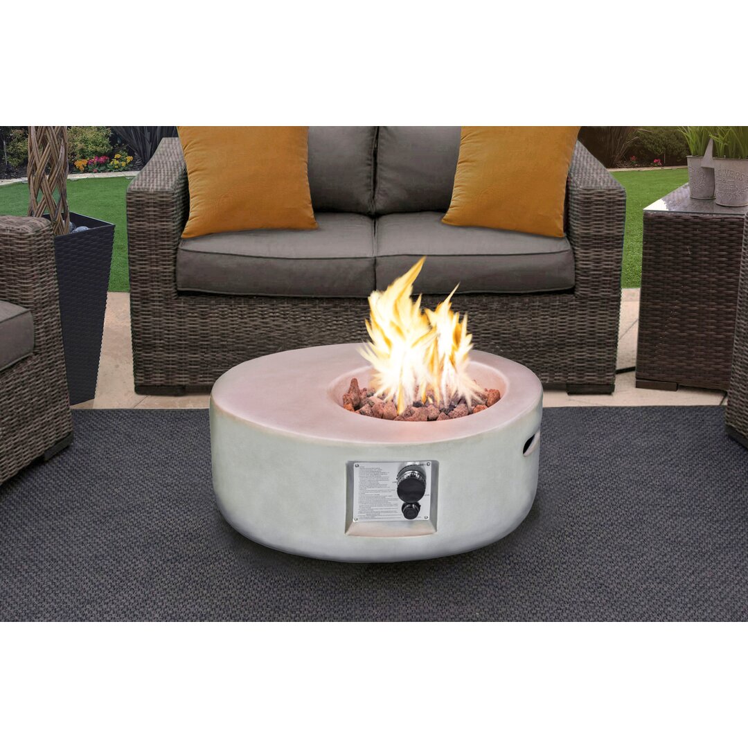 Round concrete fire pit with a smooth light grey finish, featuring a gas control knob and surrounded by decorative stones, set in a cozy outdoor seating area.