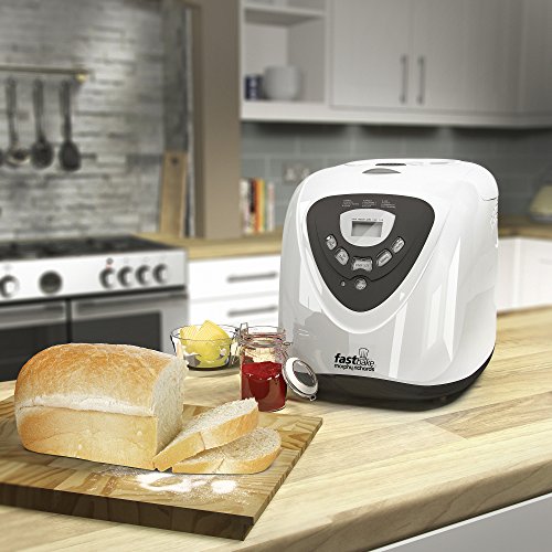 White Morphy Richards 12 Programme 600W Fastbake Breadmaker with a digital display, placed on a wooden countertop beside sliced bread, butter, and jam.