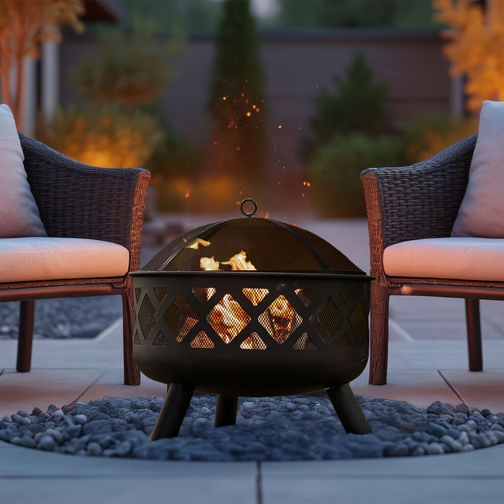 Neo Outdoor Heater Fire Pit Bowl features a black metal design with a mesh top, surrounded by smooth stones, and flanked by two wicker chairs, creating a cozy outdoor ambiance.