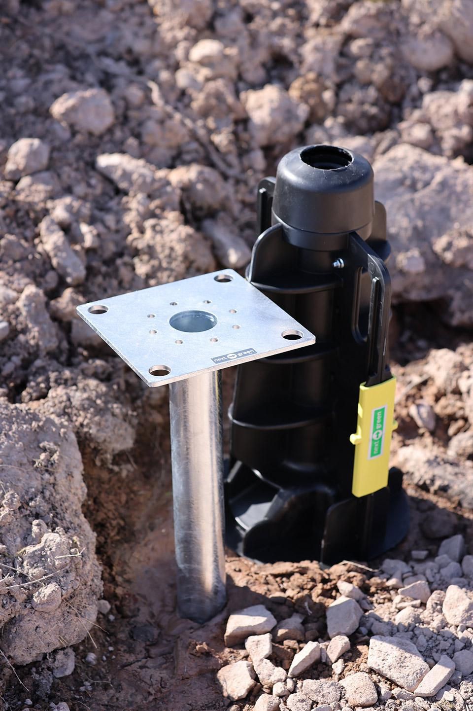Next Green Ground Moun GP60 - 160 Como features a black plastic base with a metallic pole and a silver mounting plate, designed for secure ground installation.