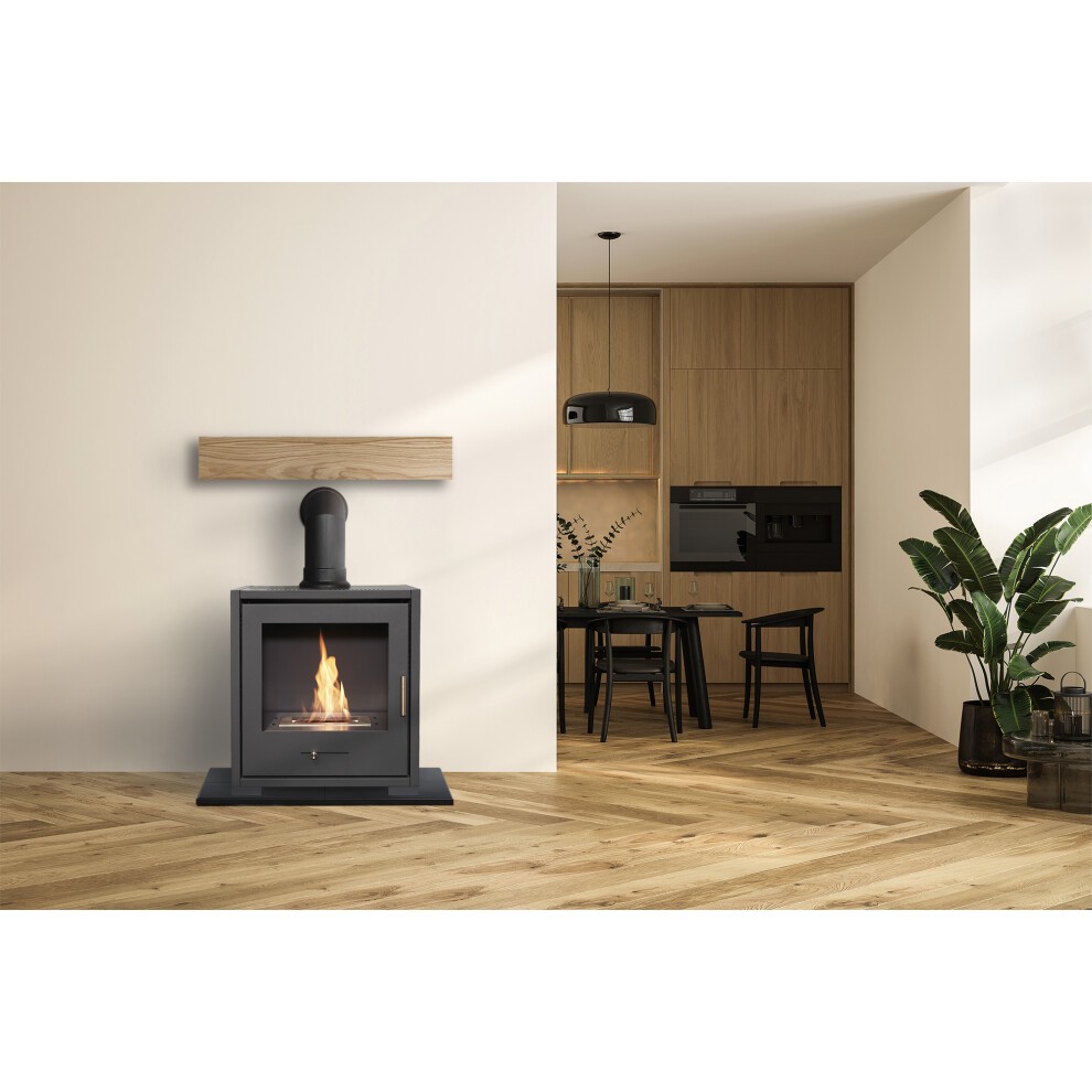 Charcoal grey OKO S3 Bio Ethanol Stove features log storage, an angled stove pipe, and a glass front, set against a modern interior with wooden accents and a plant.