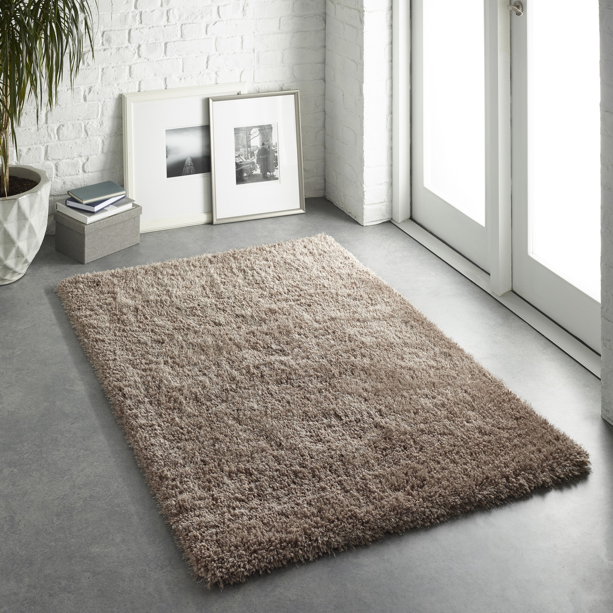 Shaggy brown rug measuring 160 x 110 cm, featuring a soft, plush texture, set against a light-colored floor with natural light streaming in from a nearby window.