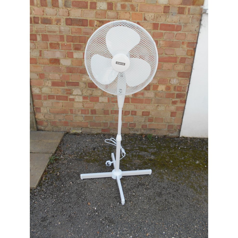 Portable 16-inch oscillating stand fan in white with a mesh guard, three blades, adjustable height, and a stable base, set against a brick wall background.