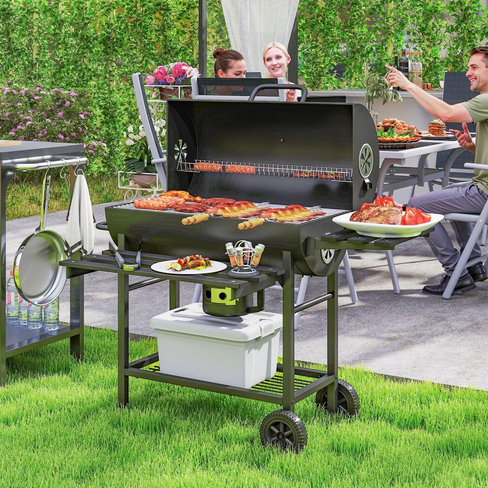 Black Outsunny charcoal BBQ grill featuring a warming rack, temperature gauge, and side shelves, set on a wheeled cart with food grilling and people enjoying a garden party.