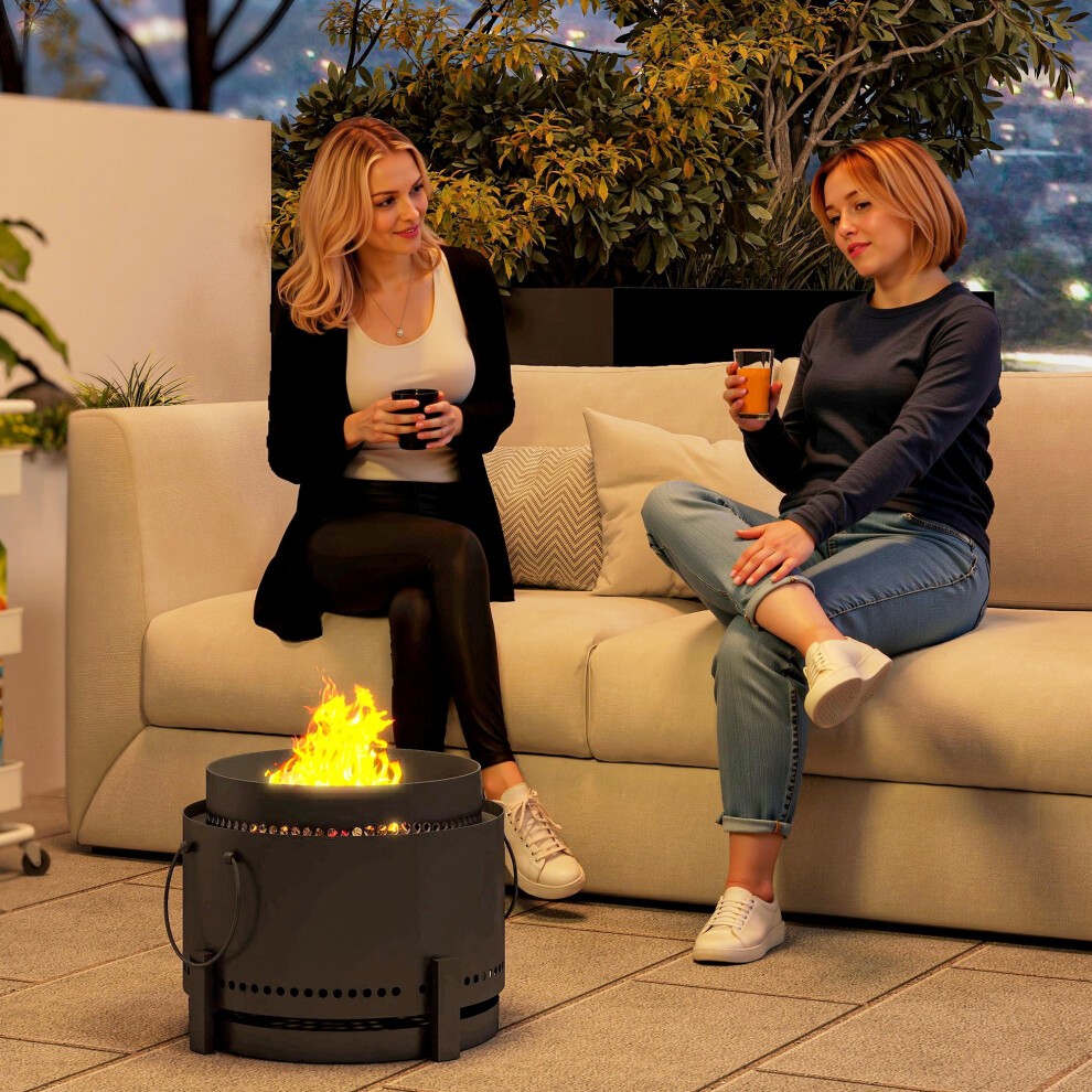 Smokeless dark grey metal fire pit with flames, featuring a circular design and ventilation holes, placed on a patio beside two women sitting on a light-colored sofa.