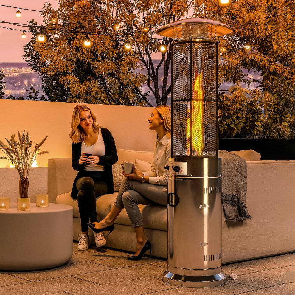 Sleek silver propane patio heater with a mesh guard, tip-over switch, and a visible flame, surrounded by cozy seating and ambient lighting in an outdoor setting.