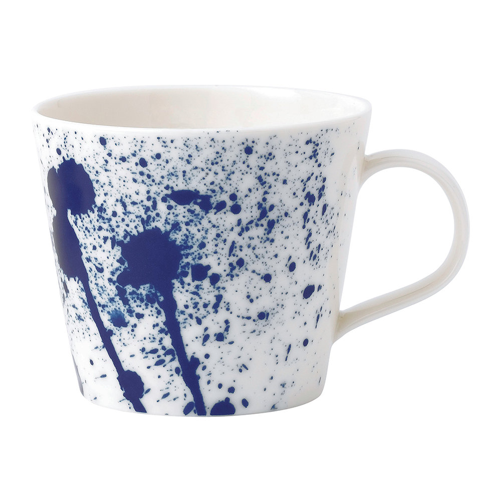 Ceramic mug featuring a white base with vibrant blue splatter patterns, showcasing a modern design and a comfortable handle.