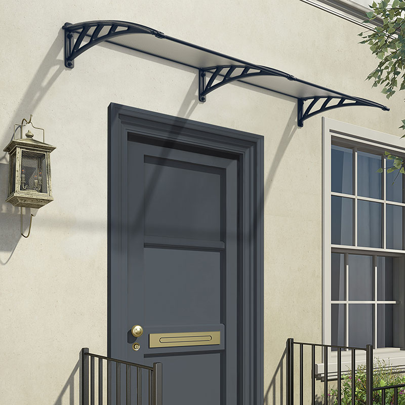 Grey twinwall door canopy with a sleek design, supported by decorative black brackets, mounted above a dark door, casting shadows on the wall.