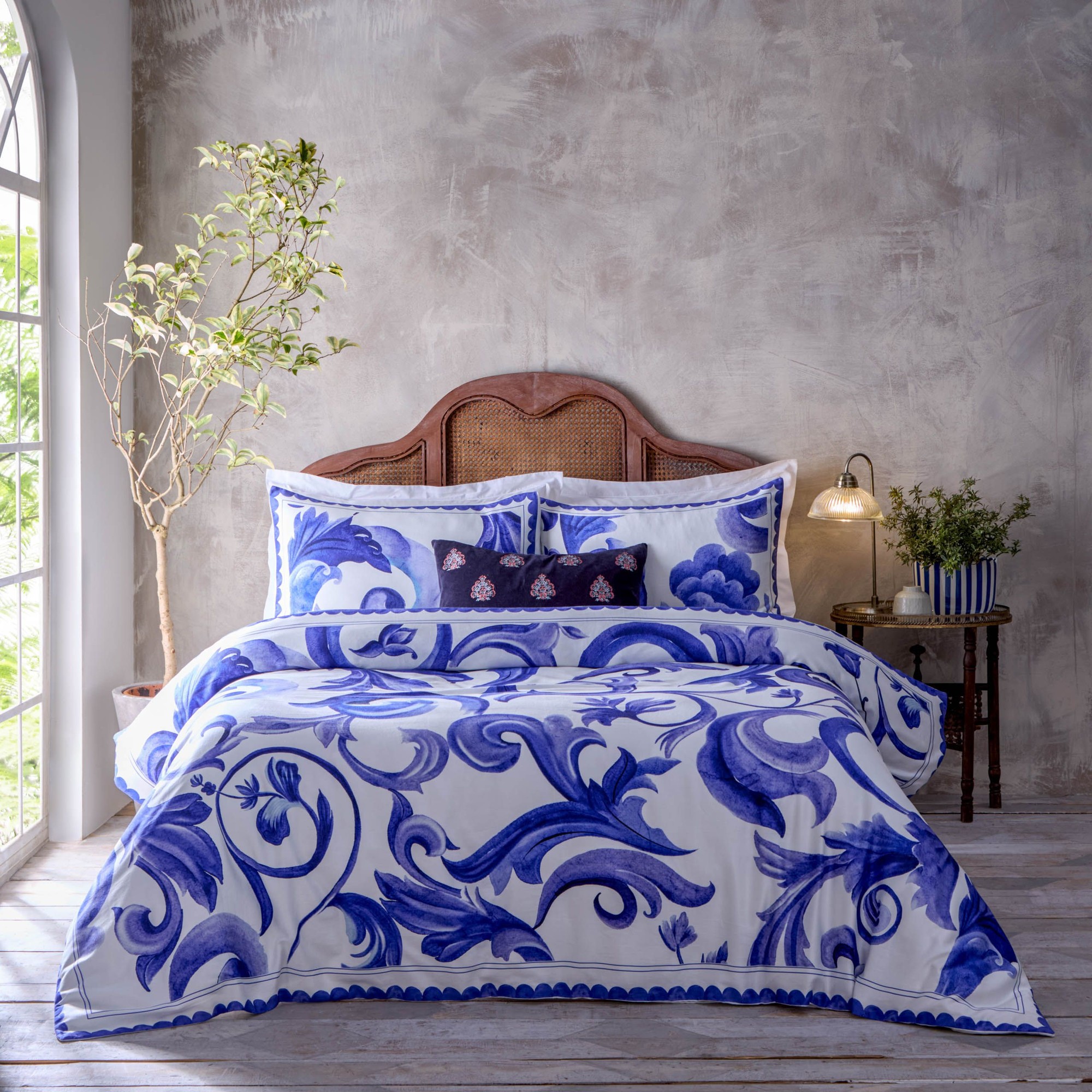 A blue and white printed duvet cover set featuring intricate floral patterns, made of 100% cotton, displayed on a bed with matching pillows in a stylish room setting.