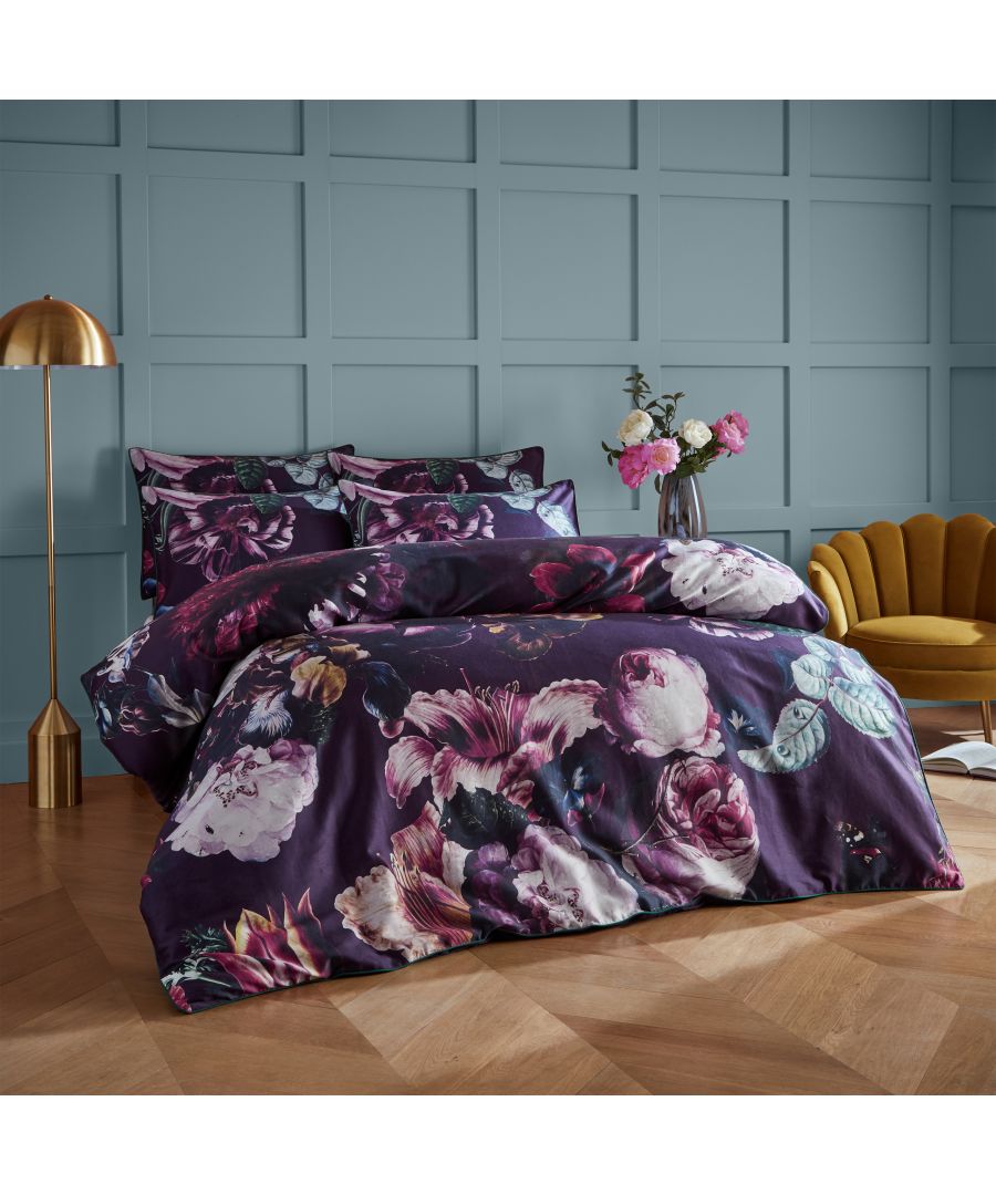 Floral duvet cover set in rich purple with vibrant pink and green flowers, made from 100% cotton, includes matching pillowcases, displayed on a wooden floor against a blue wall.