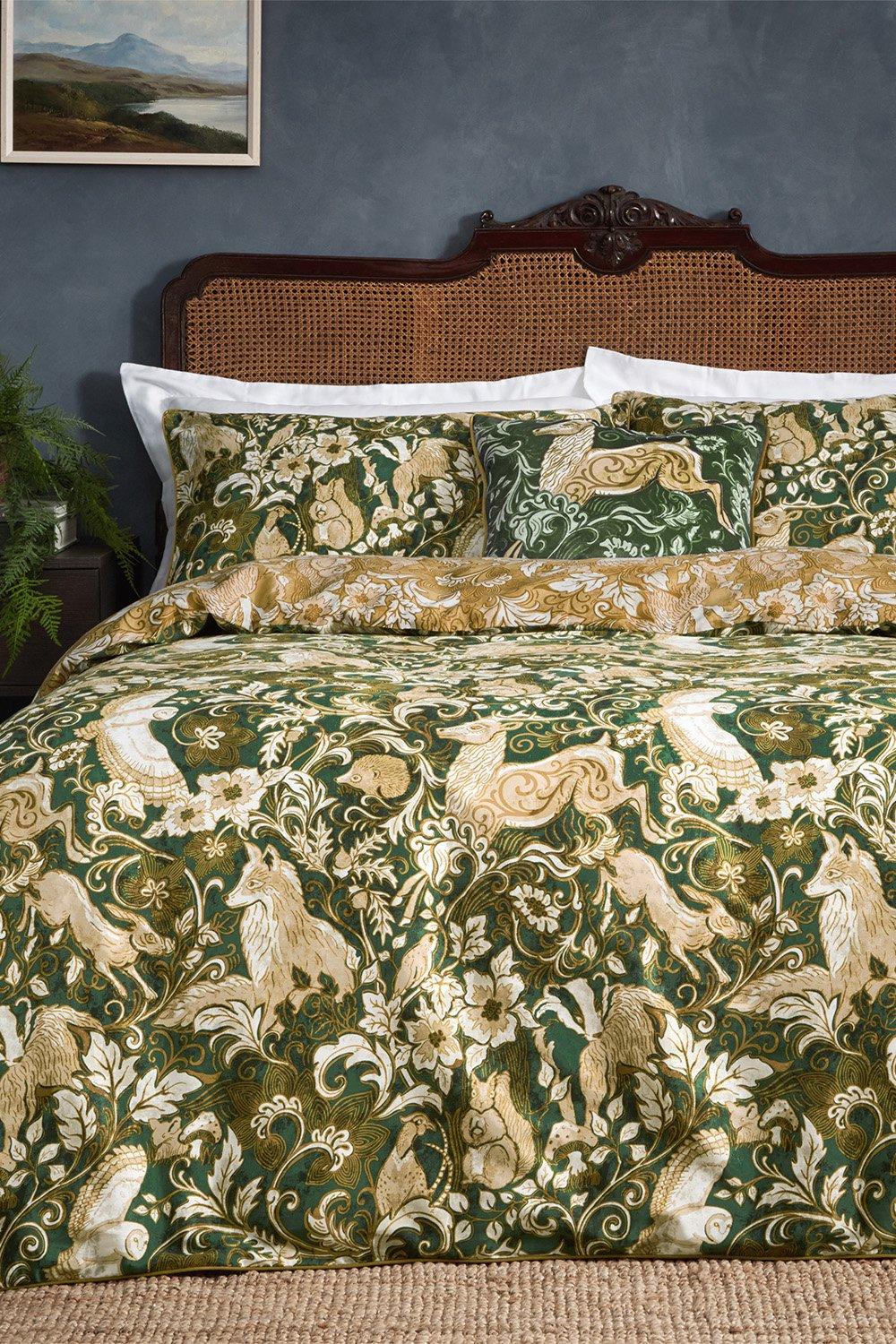 Green Paoletti Harewood Heritage double duvet cover set featuring intricate floral and animal patterns, complemented by white pillowcases and decorative cushions on a textured bed.