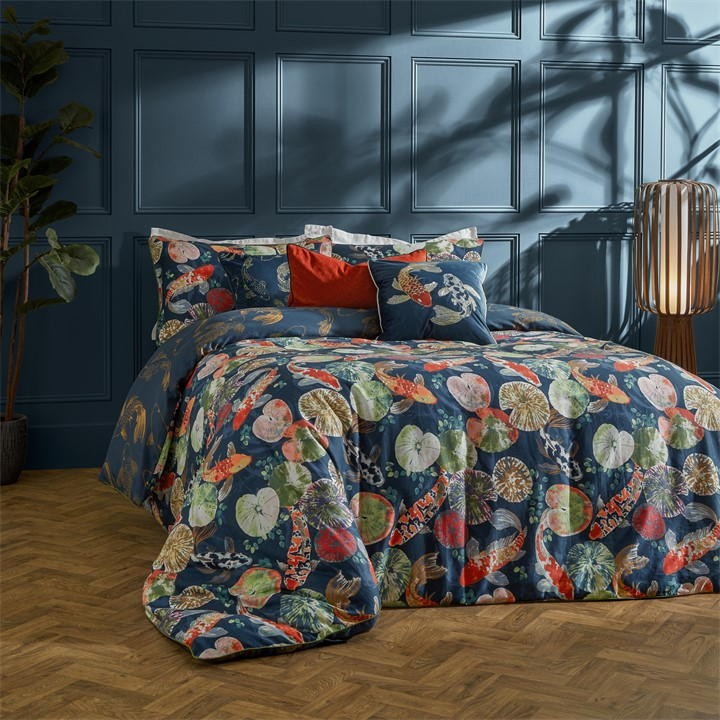 Reversible duvet cover set featuring a blue koi pond design with colorful fish and lily pads, complemented by matching pillowcases and decorative cushions in vibrant hues.