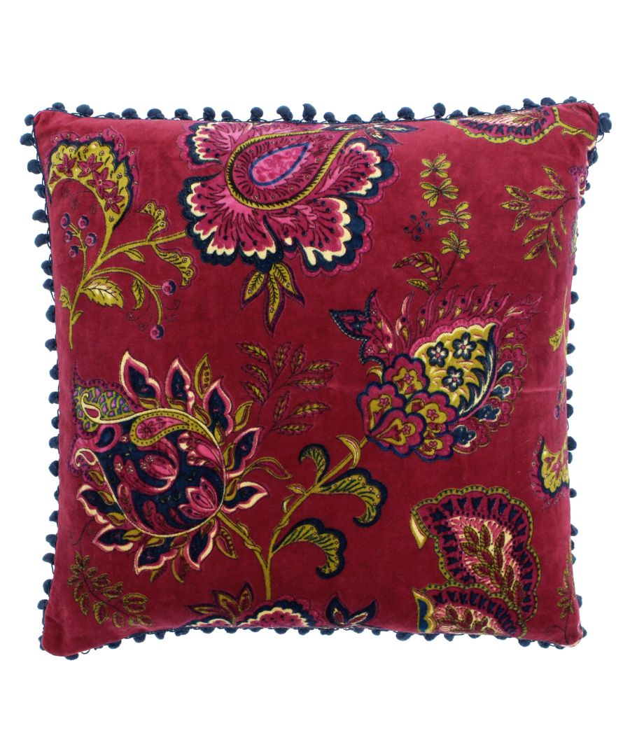 Pink velvet cushion featuring a vibrant paisley pattern in various colors, adorned with a decorative navy pom-pom trim along the edges.