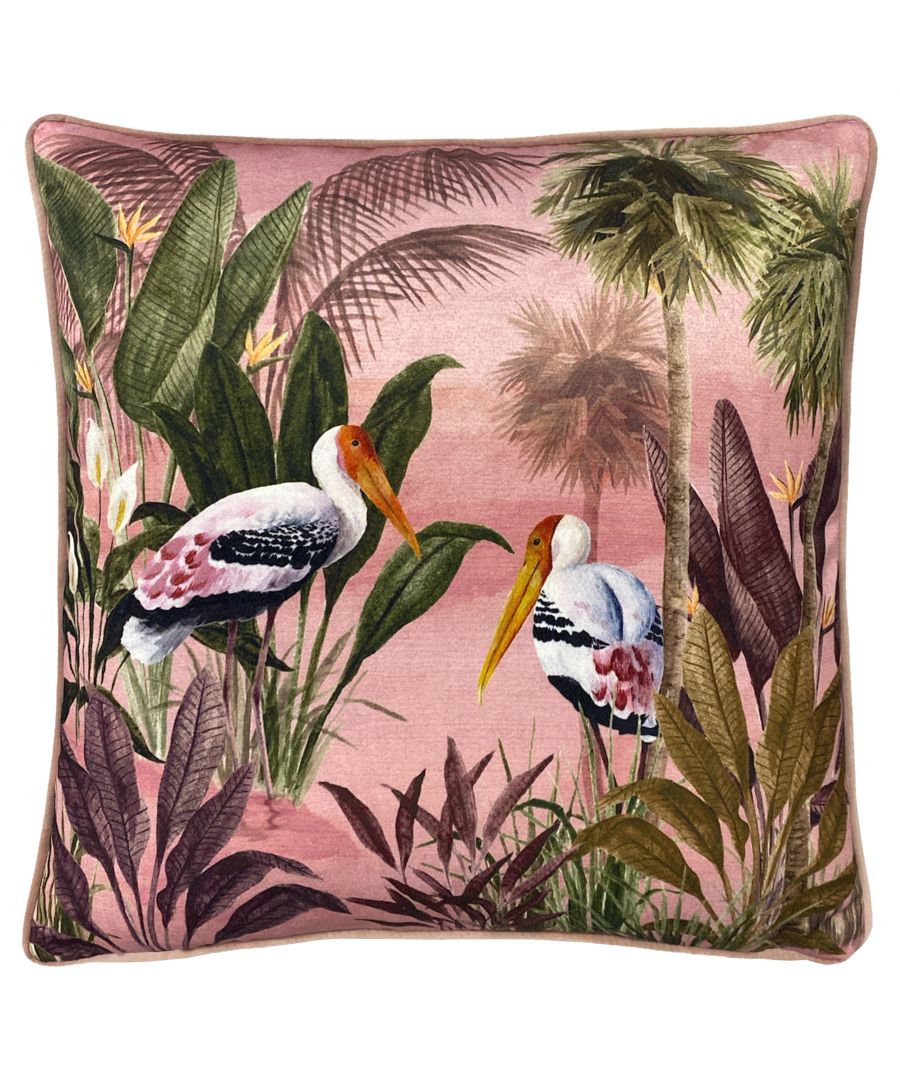 Pink velvet cushion featuring a vibrant bird print with storks, surrounded by lush greenery and palm leaves, measuring 43cm x 43cm, finished with piped edges.
