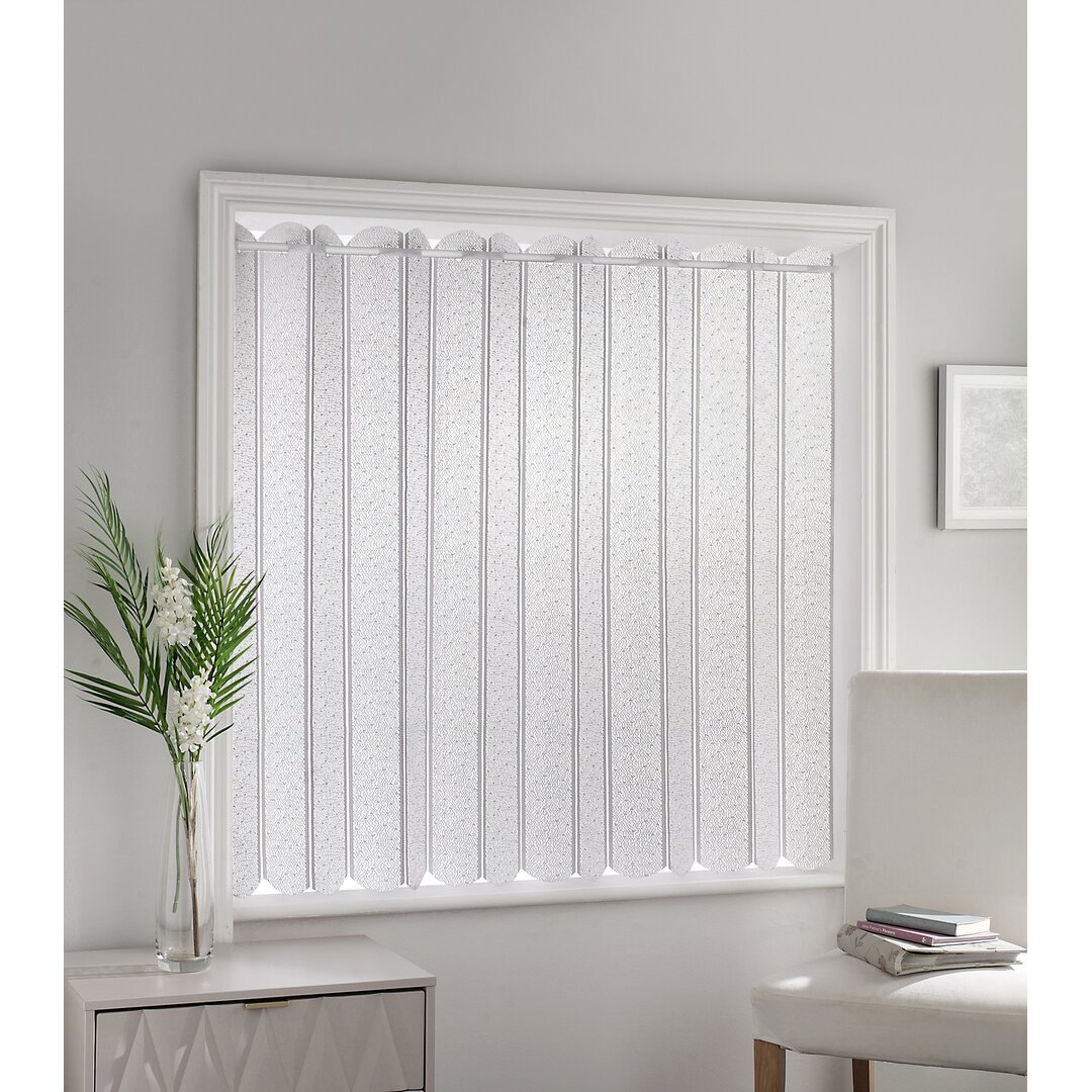 White lace louvre style blind with vertical slats, featuring a delicate pattern, installed in a window frame, complemented by a nearby potted plant and a light-colored chair.
