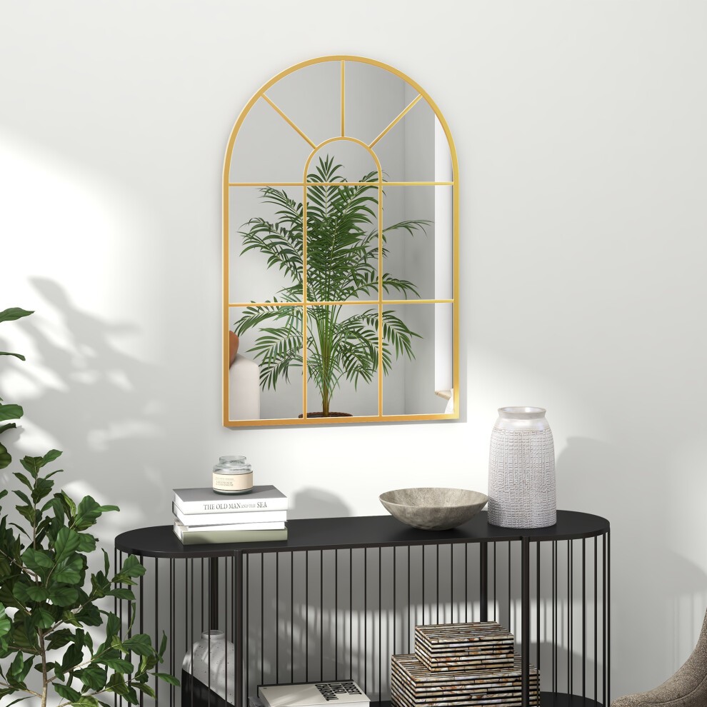 Modern arched wall mirror in gold tone, measuring 91x60cm, featuring a grid design, reflecting a green plant, displayed above a black metal console table with decor items.