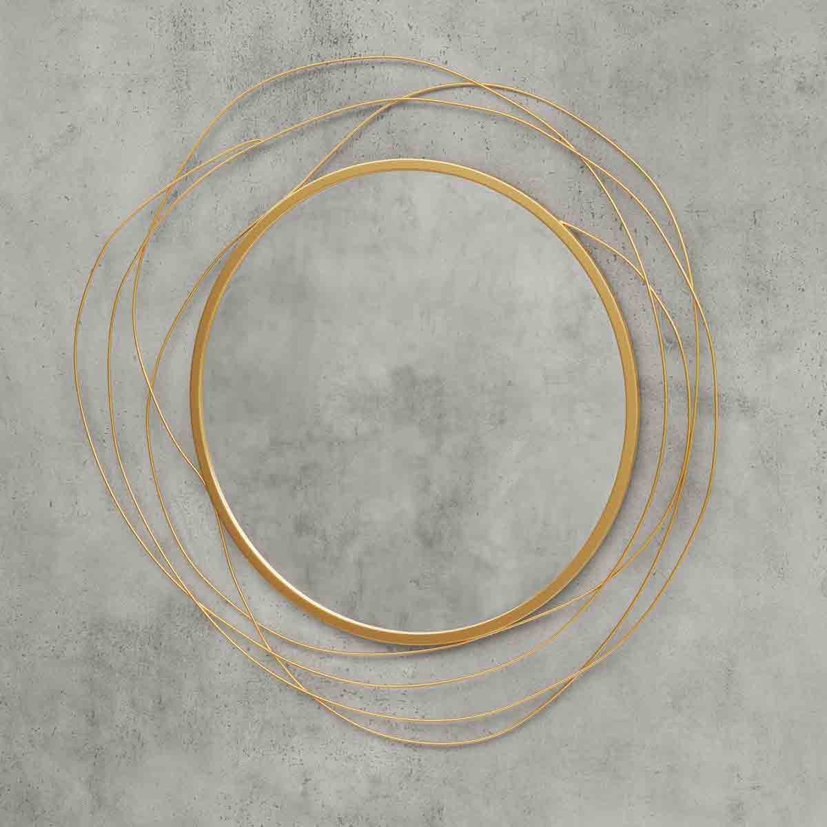 Modern 65cm round wall mirror featuring a sleek gold metal frame with abstract swirling lines, set against a textured gray wall.