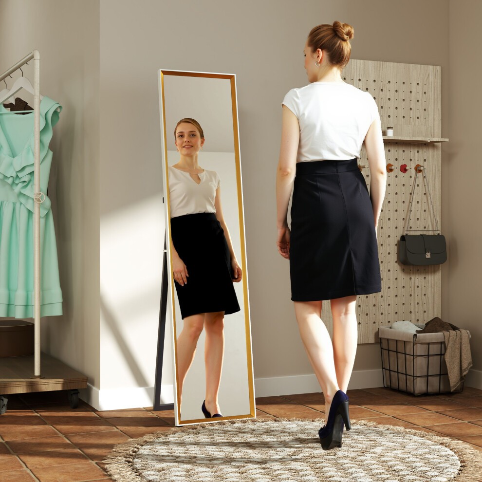 Full-length white mirror with a sleek frame, leaning against a wall, reflecting a woman in a black skirt and white top, set in a stylish room with light-colored decor.
