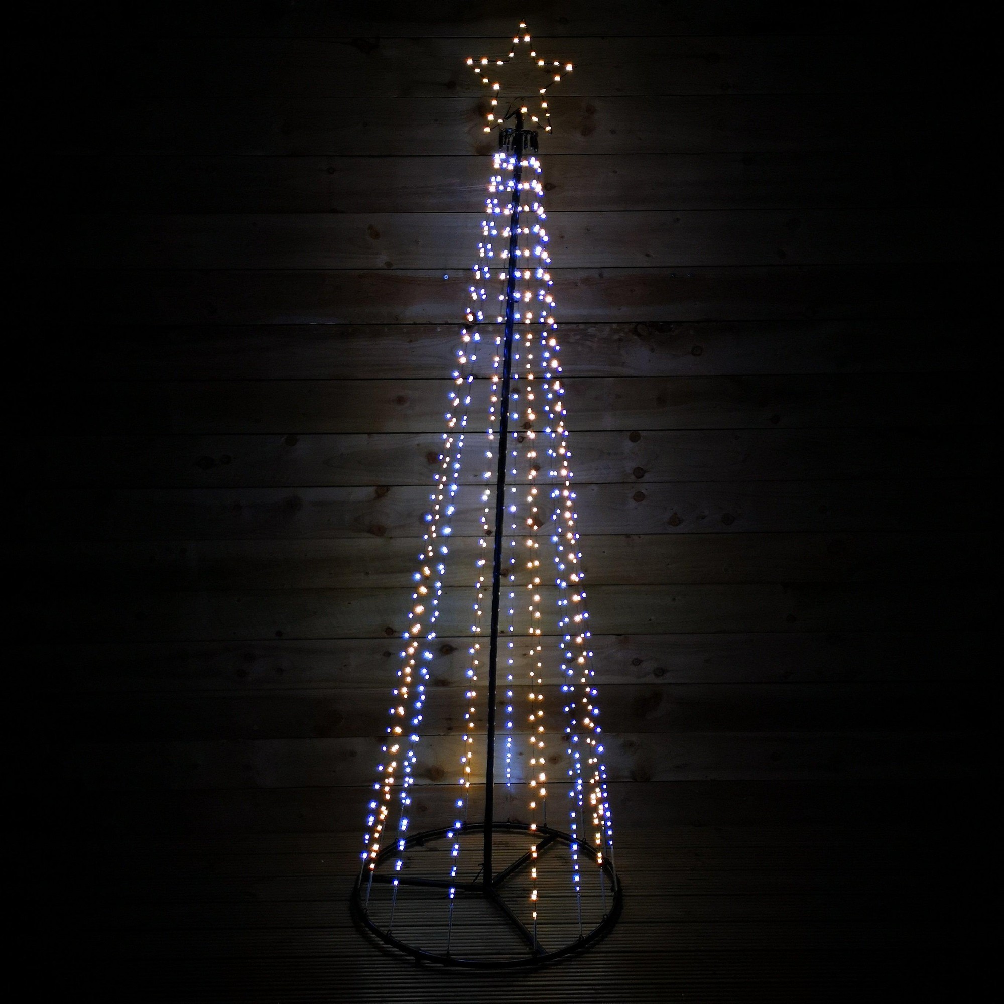13ft black pin wire pyramid maypole tree with warm and cool white LED lights, topped with a star, set against a dark wooden background.