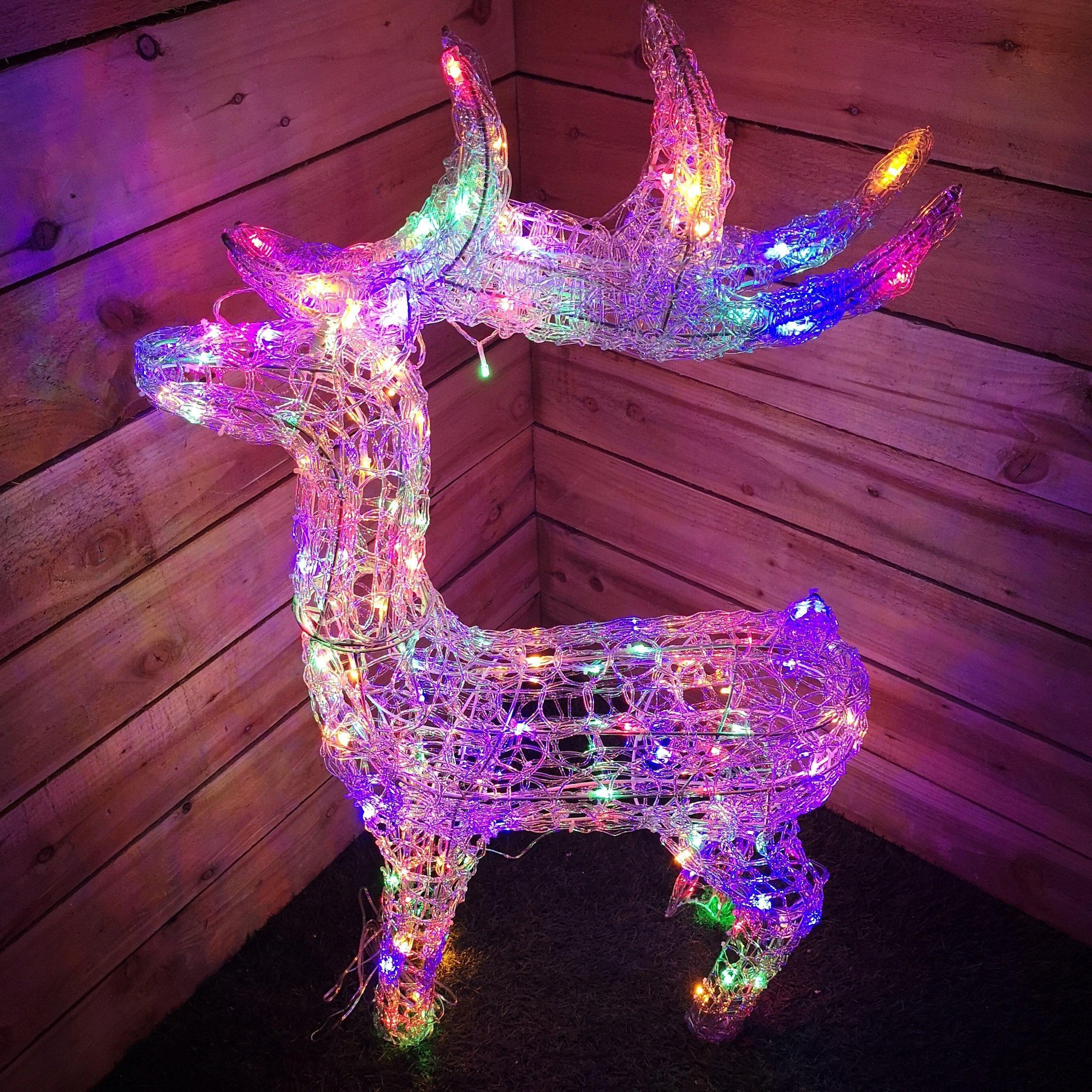 A 1.15M tall soft acrylic Christmas reindeer illuminated with 160 multi-colored LED lights, featuring a wireframe design and vibrant, glowing antlers against a wooden backdrop.