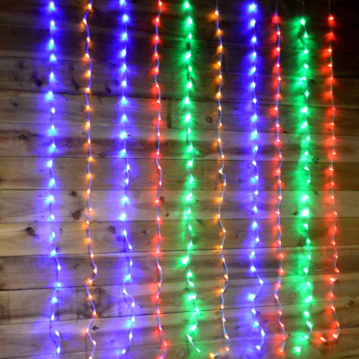 Multicoloured LED curtain lights in cascading strands, featuring vibrant blue, green, red, and orange hues, hanging against a wooden backdrop, measuring 1.5m x 2m.